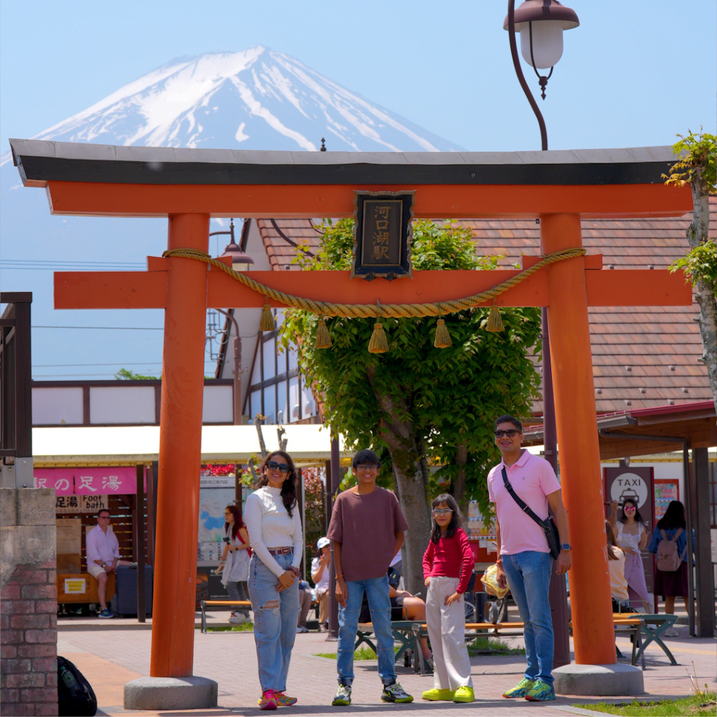 Indian family posing in front of the torii gate at Kawaguchiko Station with Mt. Fuji in the background.