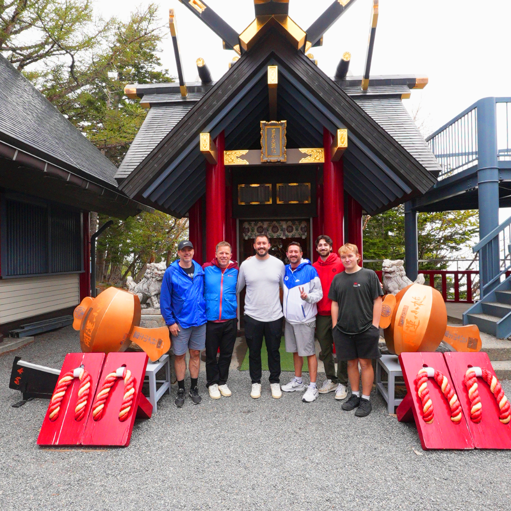 Six American team members standing in front of a shrine at Mt. Fuji’s 5th Station during a company photo tour in Japan.