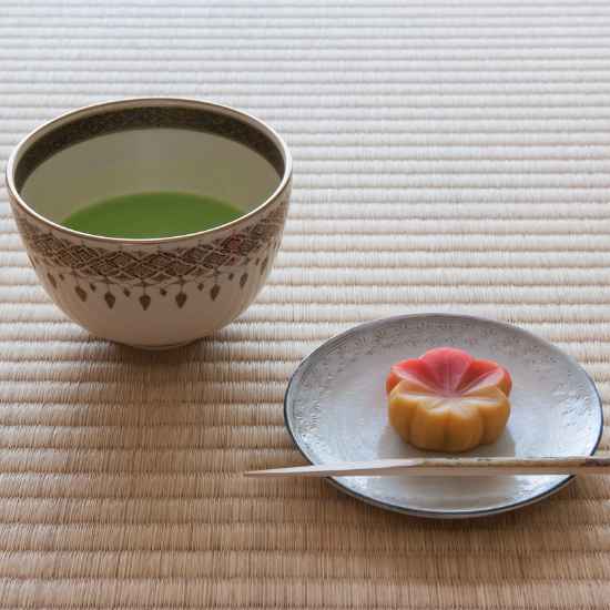 A bowl of traditional Japanese matcha green tea served with an artistic wagashi sweet.
