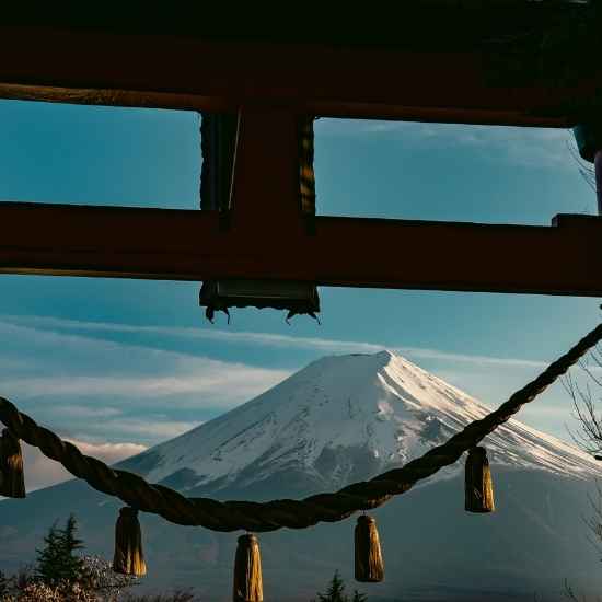 A majestic view of Mt. Fuji framed by a traditional wooden Torii gate with a sacred rope.